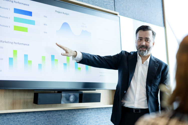 Great Discussions to Create Great Solutions for Your Business Management Strategy. Business Executive giving a presentation on marketing performanc...