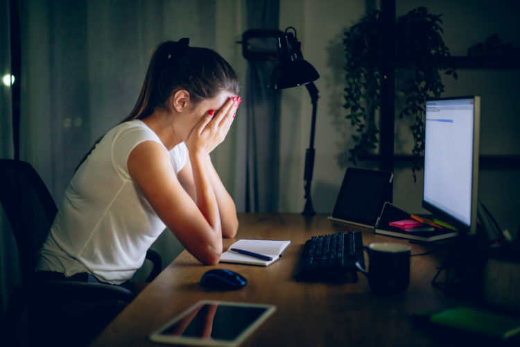 Overworked young woman at her desk late at night